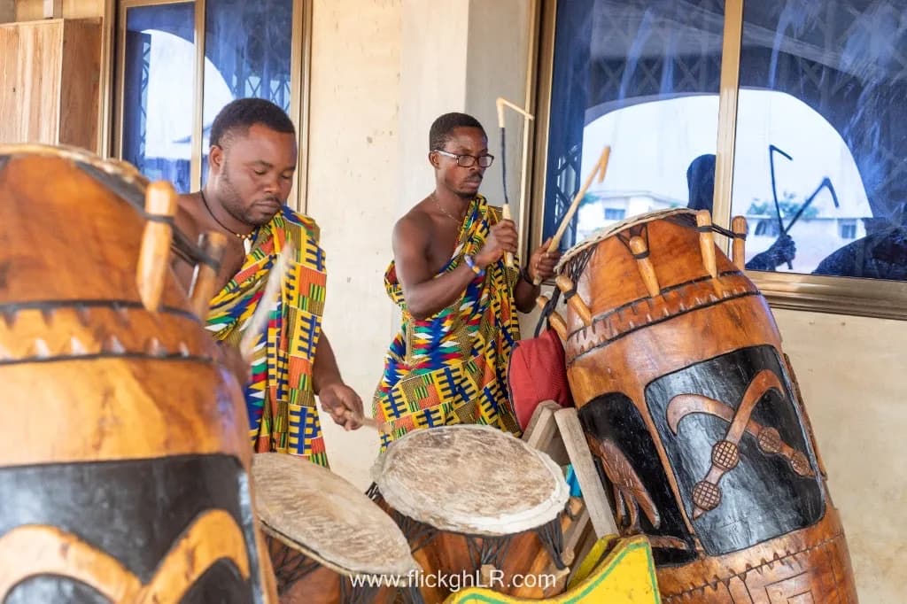 Traditional Ghanaian drummers in Kente cloth performing at a community celebration.
