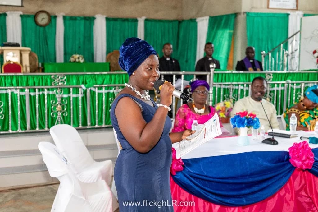 A woman addresses the gathering from the microphone at a church event.
